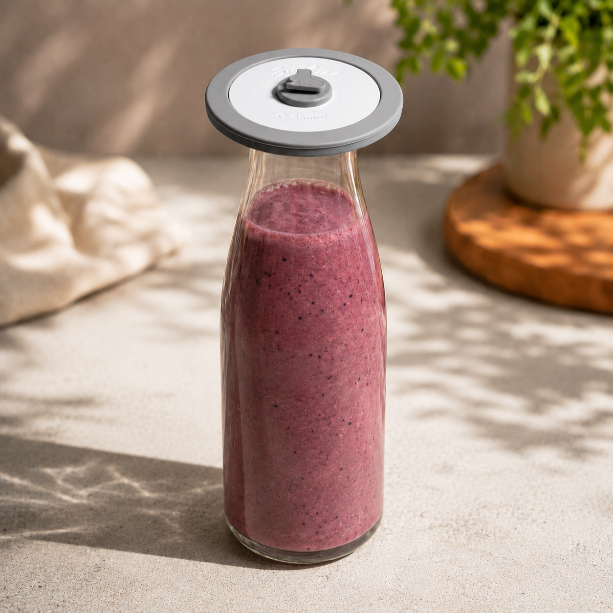 Glasflasche mit Beerensmoothie und aufgesetztem AnySeal Vakuumdeckel in einer sonnigen Küche